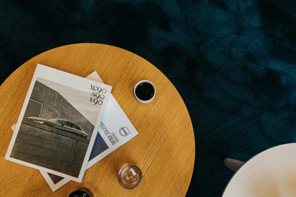 Top view of a wooden table with a black coffee cup and magazines, creating a cozy setting.