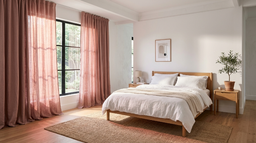 Dusty rose bedroom ideas with floor-to-ceiling linen curtains in a neutral white bedroom with natural light