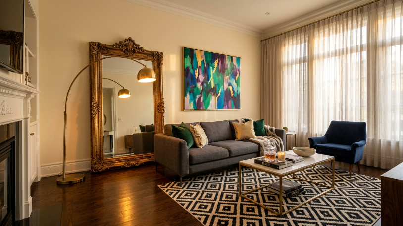 Modern charcoal sofa and ornate vintage gilded mirror mixed together in a Hollywood Regency ideas living room.