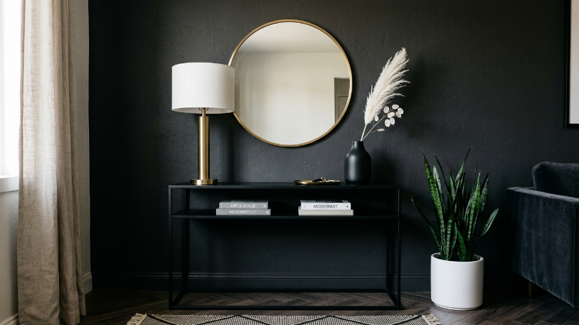 Gold mirror and black console table styled in a completed black and gold room with dark leafy plant